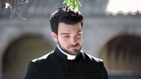 Portrait Of young Catholic Priest smiling at camera outdoor