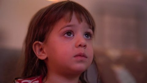 A young girl watching television on a living room couch
