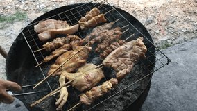 Thai Street Food : charcoal grilled roast chickens, pork on the stove half cut oil tank with smoke. Thai style food. Thai BBq or 