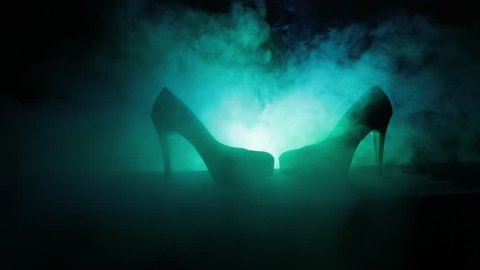 Black suede high heel women shoes on dark toned foggy background. Close up. Women power or women domination concept. Selective focus. Slider shot
