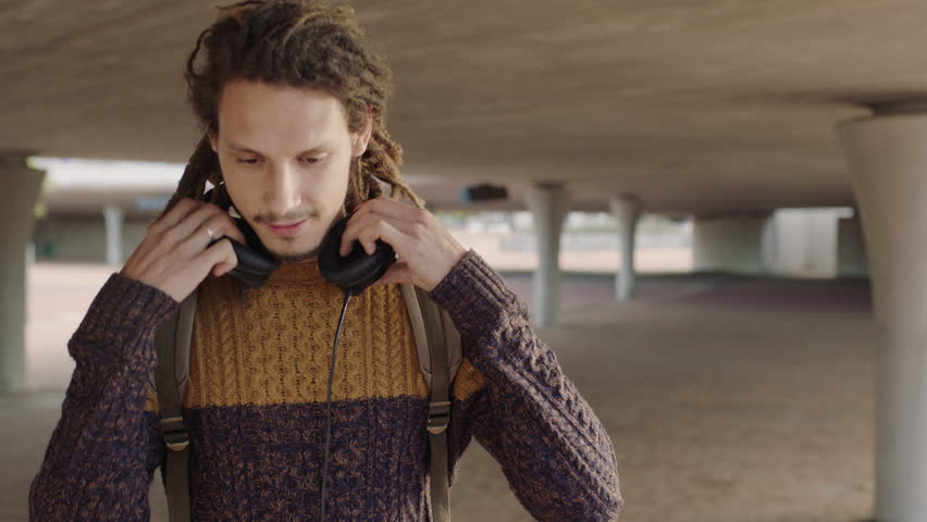portrait of young mixed race man student with dreadlocks wearing headphones happy smiling