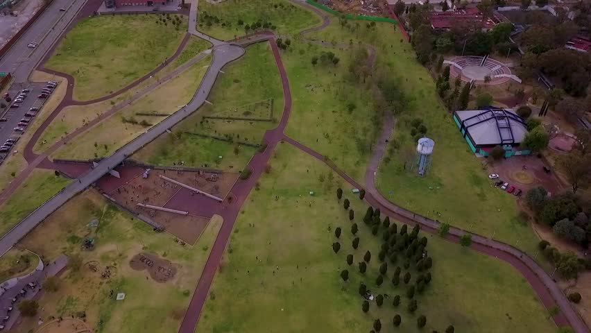 Aerial flight over the gigantic Bicentennial Park that is located on the outskirts of the refinery subway station, families playing in the green areas
