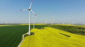 Aerial view of wind turbines. Rapeseed field in bloom. Renewable energy