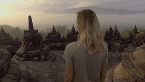 4K video of young woman wandering in Borobudur ancient buddhist temple at sunrise. People travel discovery Asia concept