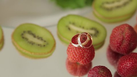 Golden rings on strawberry fruit - wedding concept