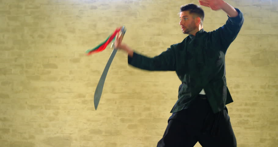 Kung fu fighter practicing martial arts with sword in fitness studio 4k