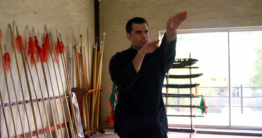 Kung fu fighter practicing martial arts in fitness studio 4k