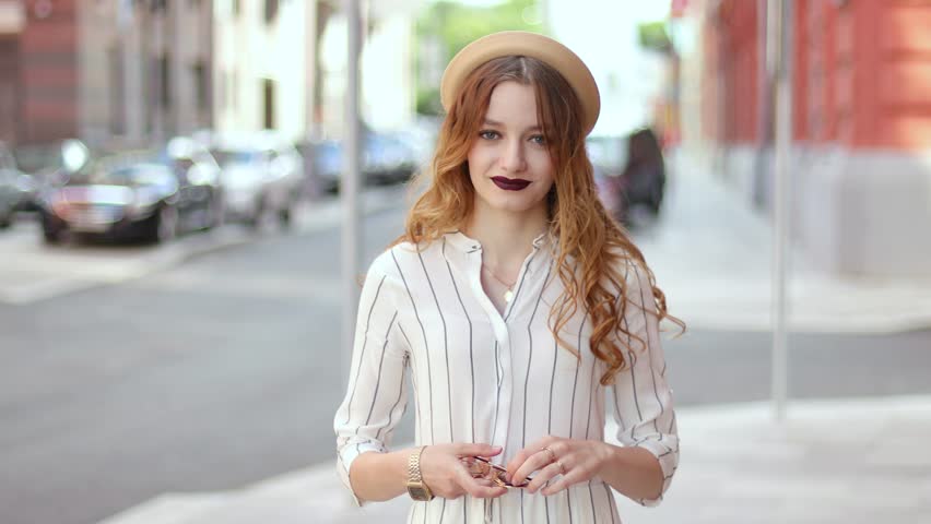 Beautiful smiling woman in a hat with a lovely look looking at camera and put on sunglasses