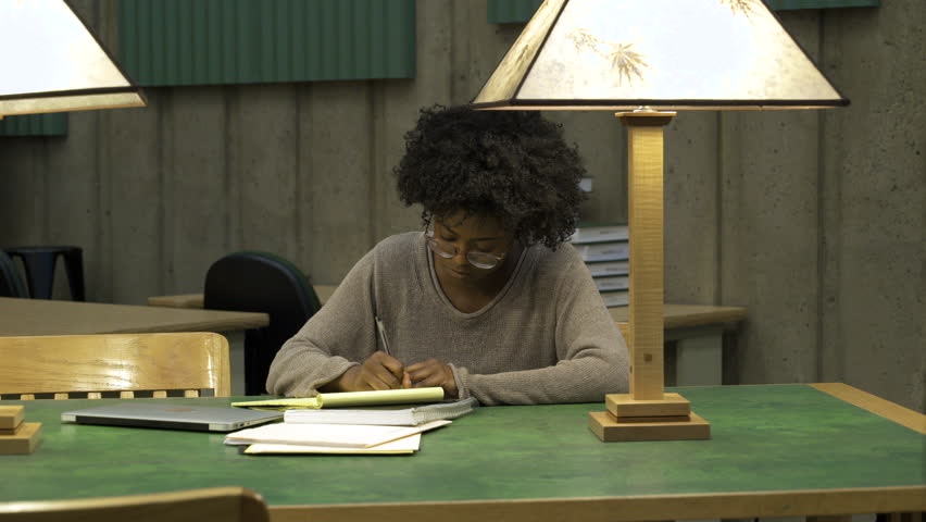 Young woman writing in notebook in college.
