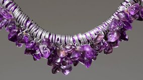  Amethyst necklace swaying on a grey background. Violet.