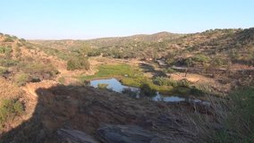 HD high quality summer morning video of African sunrise over small water dam surrounded by bushy hills in Daan Viljoen National Reserve in Khomas Hochland area near Windhoek, Namibia's capital, Africa