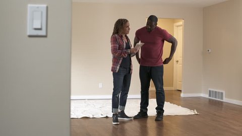 Couple standing in room of new home, looking at colour swatches.