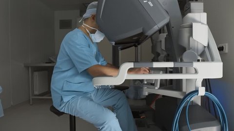 Surgeon operating medical robotic surgery device. Professional surgeon perform remote manual control of robotic arm and manipulators. Minimally invasive surgical system. Modern medicine, medical robot