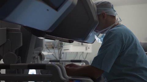 Surgeon operates robotic arm of medical surgical robot using remote controllers and looking inside patient. Manual control by Minimally Invasive Surgical System