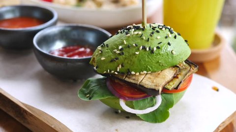 Closeup Of Avocado Vegan Burger With Vegetables In Healthy Cafe.
