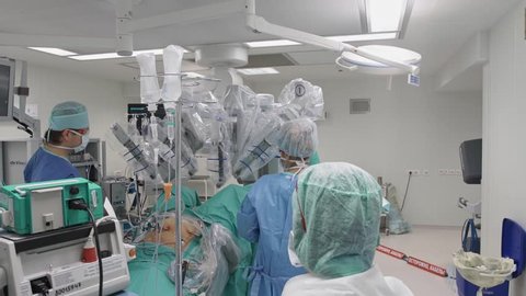 Operating room, team of surgeons prepares patient to cancer removal surgery via Minimally Invasive Robotic Surgery. Hi-tech medical robot