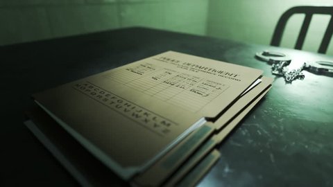Closeup of metal handcuffs and case files on a table in the interrogation room