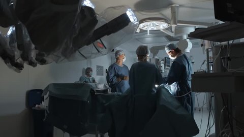 Operating room, team of surgeons prepares patient to cancer removal surgery via Minimally Invasive Robotic Surgery. Hi-tech medical robot, modern medicine, futuristic medical equipment, operation