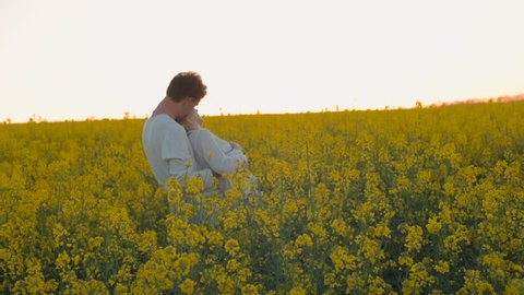 Happy young couple in yellow rape flowers field during sunset