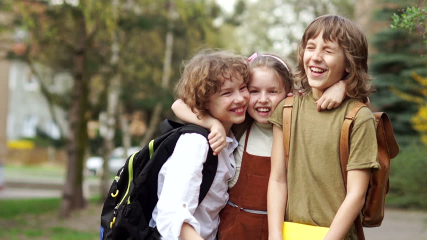 Brothers and sister cheerfully embrace each other on the way to school. Day of knowledge. Back to school. Family education Royalty-Free Stock Footage #1010833253
