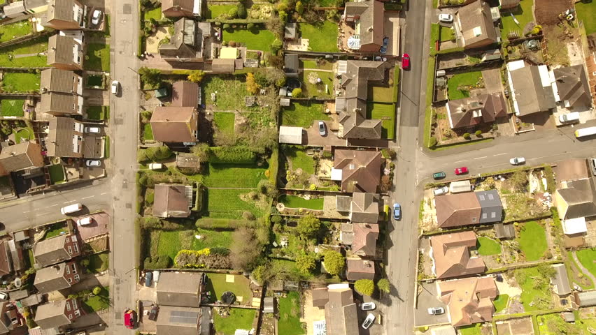 Aerial footage over a classic British housing estate, English houses and homes from above. Middle class and council building and gardens. 