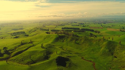 Aerial view of north island of New Zealand, picturesque lush green hills of Shire/Hobbiton (The Lord of the Rings and Hobbit location), fantasy landscape at sunset time, 4k UHD
