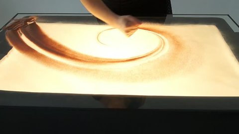 Drawing with sand. Drawing sand on a white screen. Sand Artist. Hands draws