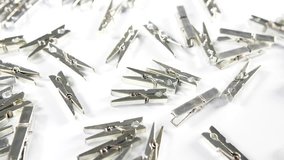 4k silver metallic pegs scattered on a white surface background. close up image of craft and scrap book accessories for school office or play