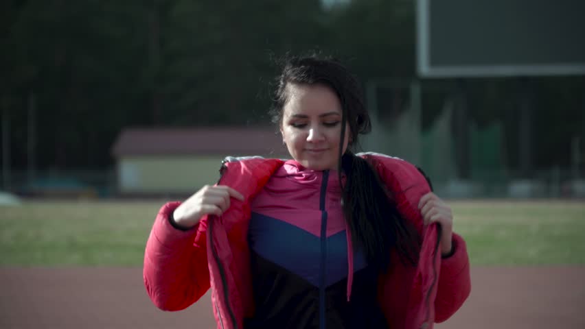 shapely athletic girl brunette takes off a red jacket