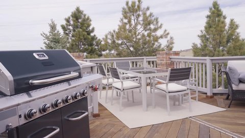 Six burner outdoor gas grill with open lid on back patio.
