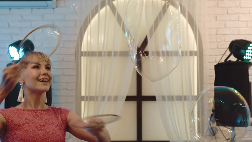 Young cute girl playing with big soap bubbles, doing show, close-up 