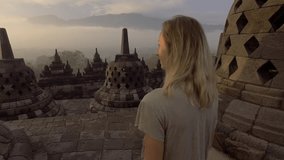 4K video of young woman wandering in Borobudur ancient buddhist temple at sunrise. People travel discovery Asia concept