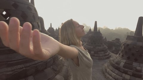4K resolution video of travel girl embracing sunrise at Borobudur temple, Indonesia . People discovery Asia concept 