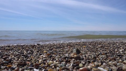 Rocks and pebbles along beach lake shore with wave washing on shore