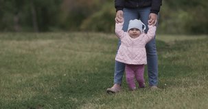 Happy mother and daughter walking outdoor. Child and parent in a spring park. raw s-log2 video footage in Ultra HD video 4k (4096x2160)