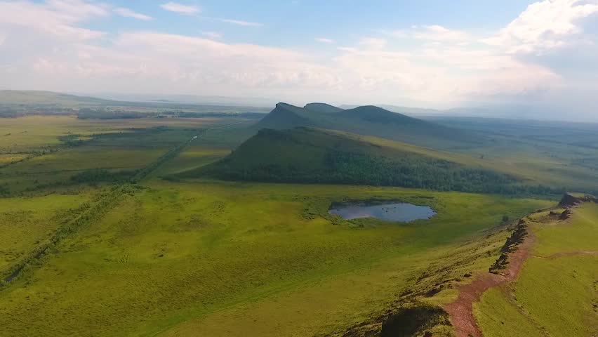 Aerial view of the mountain range Sunduki, green fields sky before the storm in the Republic of Khakassia. Russia