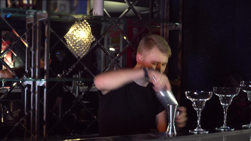 The bartender performs tricks with bottles and glasses