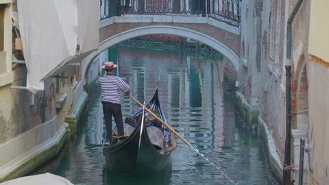 Venice Italy 2017 November 14: An empty gondola being rowed in the canal in Venice Italy with the big buildings on the side of the canal
