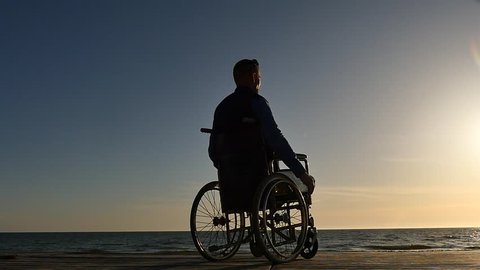 disabled man in wheelchair near sea coast panoramic shot silhouette