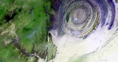 Very high-altitude overflight aerial of the Richat Structure, a geological formation in the Maur Adrar Desert, Mauritania. Clip loops and is reversible. Elements of this image furnished by NASA