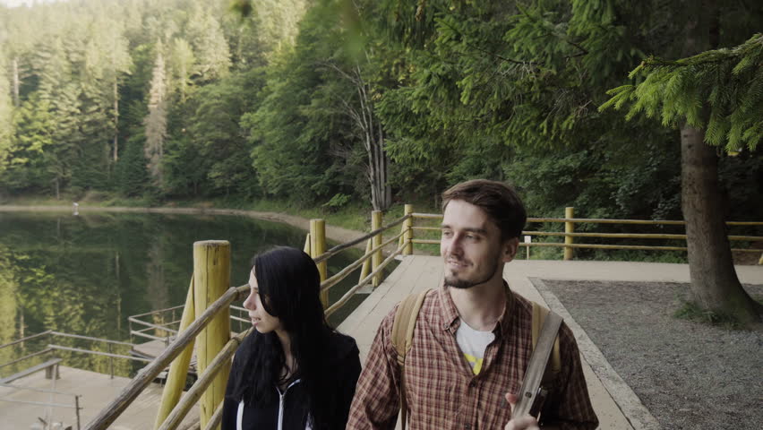 A woman and a man are walking, a couple in love, walking in the mountains by the lake