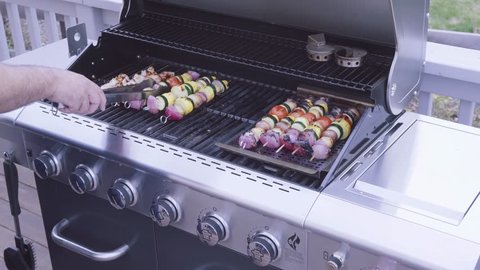 Step by step. Grilling veggie skewers and chicken kebabs on outdoor gas grill.