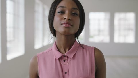 slow motion portrait of young confident african american woman looking serious pensive wearing pink stylish blouse in new apartment close up