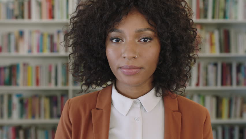 close up portrait of stylish african american business woman intern looking serious pensive at camera in library bookshelf background real people series Royalty-Free Stock Footage #1010918411