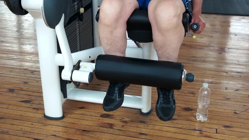Close up man exercising at gym. Male athlete doing leg exercise. Perfect body through efforts.