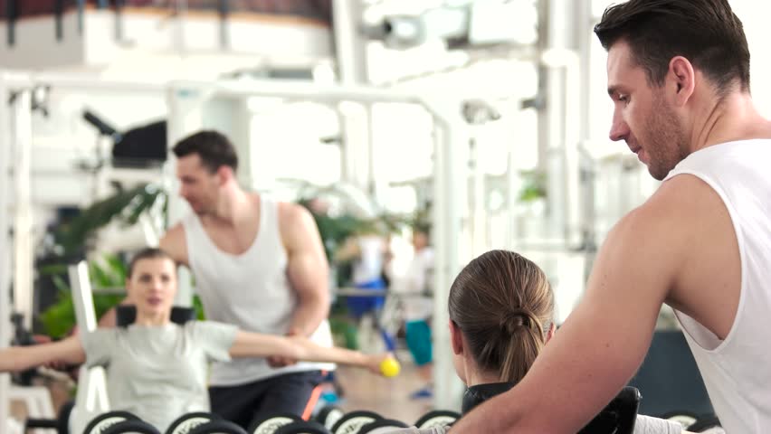 Woman training at gym with personal trainer. Woman training with dumbbells with a help of fitness instructor.