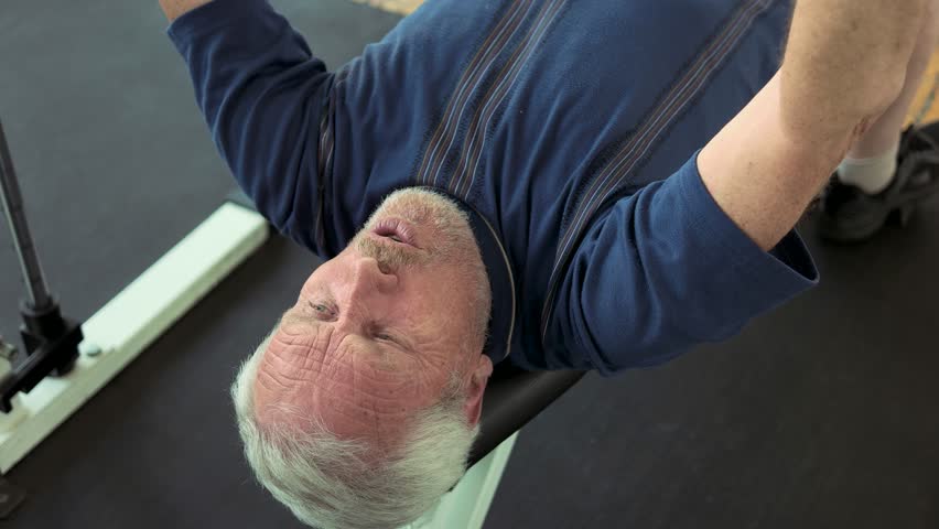 Senior man doing bench press exercise. Male pensioner lifting weight at gym close up. Reasons to strat lifting weights.