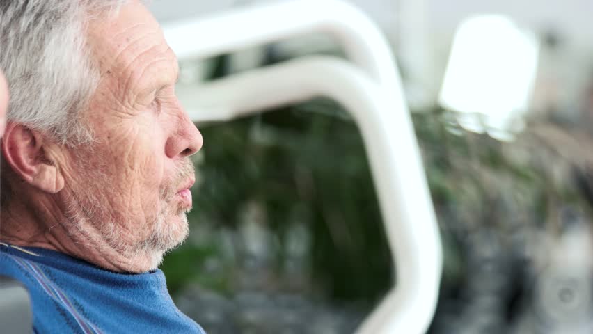 Close up old man doing chest exercise at gym. Senior man training on machine at fitness center. Strength training benefits for ageing bodies.