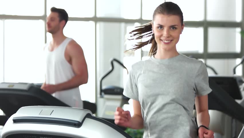 Young happy woman working out at gym. Slow motion young woman training at fitness club and looking at camera. Weight loss concept.