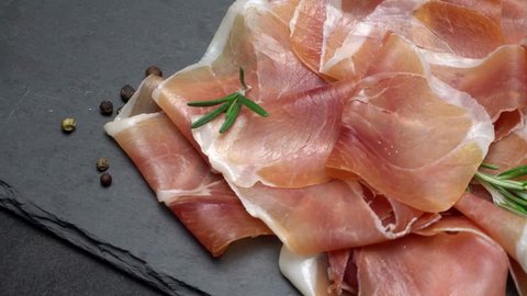 sliced prosciutto or jamon meat on concrete background